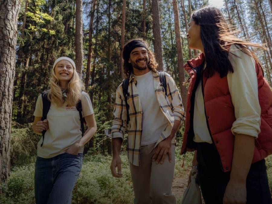 Three smiling hikers in casual autumn hiking clothes in the sunny forest