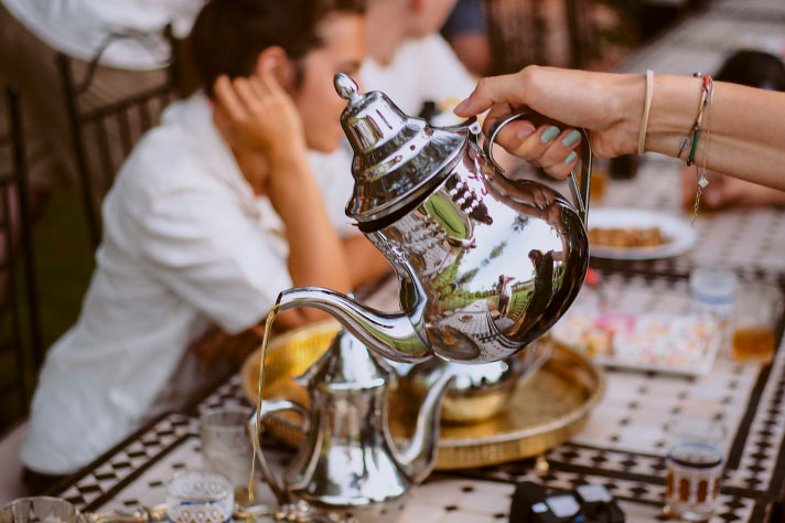 A person serving tea from a silver teapot